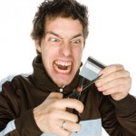 Young male about to cut a credit card on a white background Young male about to cut a credit card on a white background